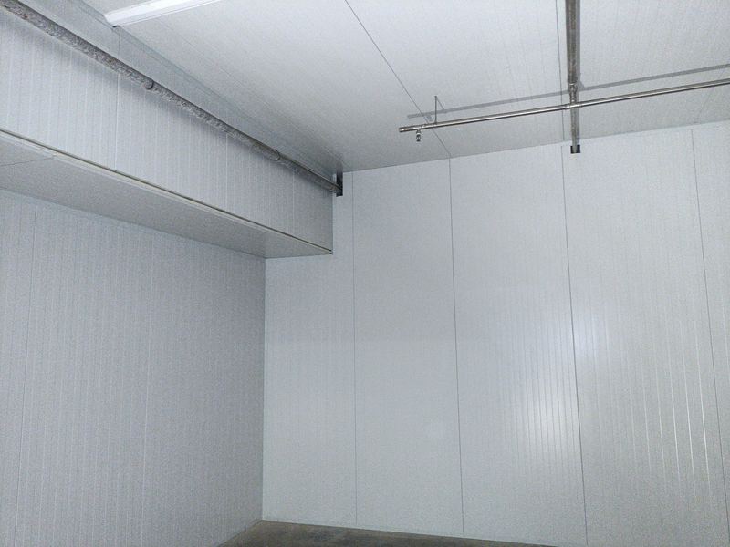 Cámara frigorífica con techo aislado montado y la instalación vista bajo el forjado.